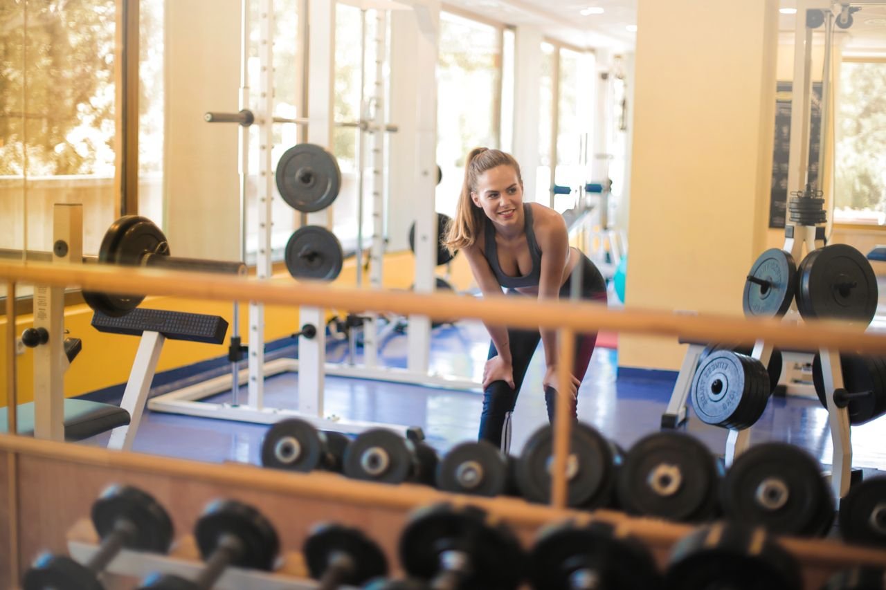 Fit woman in a gym with weights, showcasing strength and fitness lifestyle.